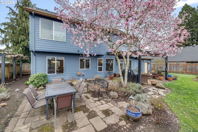 back of property with a fenced backyard, a lawn, outdoor dining area, and a patio
