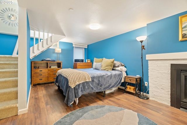 bedroom featuring wood finished floors and a fireplace