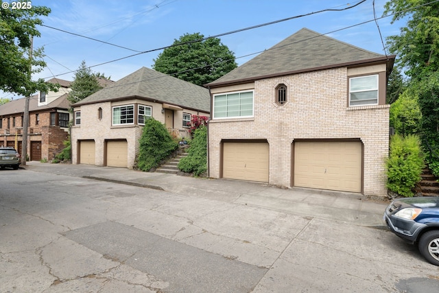 view of front facade featuring brick siding, roof with shingles, and an attached garage