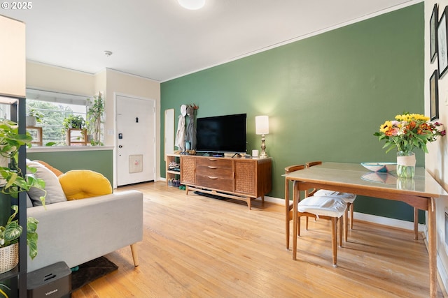 living room with light wood finished floors, baseboards, and ornamental molding