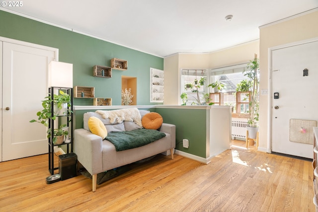 living area featuring radiator, ornamental molding, wood finished floors, and baseboards