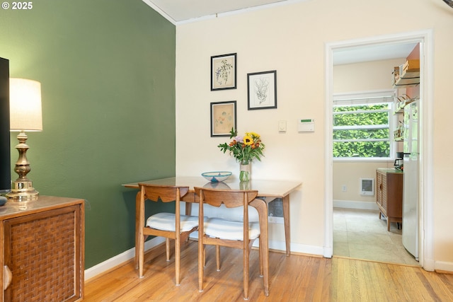dining area with wood finished floors, baseboards, and ornamental molding