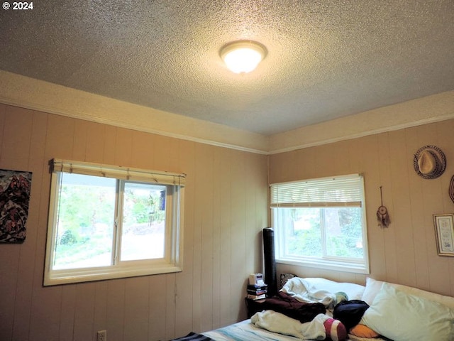 bedroom featuring a textured ceiling and wooden walls