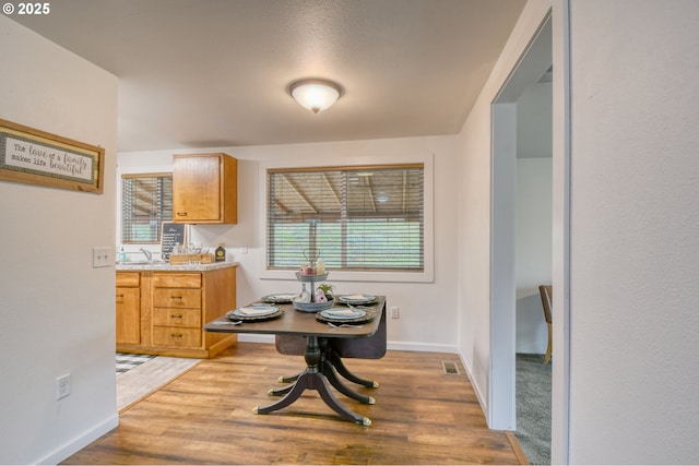 dining space with visible vents, light wood-style flooring, and baseboards