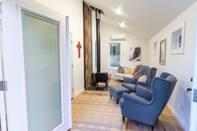 37459 Boulder Flat Ln, Halfway, OR 97834 - living room with a wall mounted AC, a wood stove, wood finished floors, vaulted ceiling, and baseboards