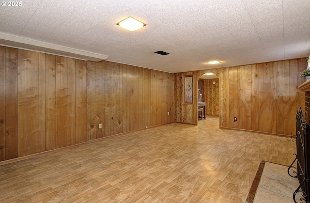 basement with a brick fireplace, hardwood / wood-style floors, and wood walls