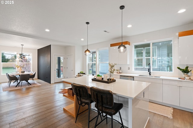 kitchen featuring modern cabinets, white cabinets, a kitchen island, light countertops, and a sink
