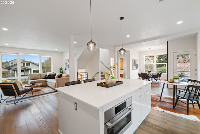 kitchen with recessed lighting, hardwood / wood-style floors, oven, and a kitchen island