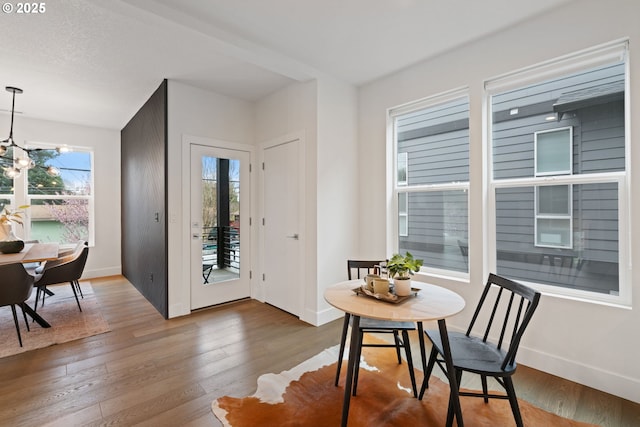 dining space with a chandelier, baseboards, and wood finished floors