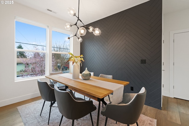 dining room featuring visible vents, a notable chandelier, wood finished floors, and a healthy amount of sunlight
