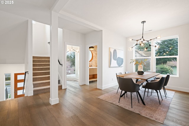 dining space featuring a healthy amount of sunlight, a notable chandelier, wood finished floors, and stairs