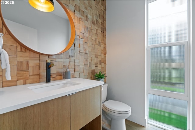 half bathroom with tasteful backsplash, toilet, and vanity