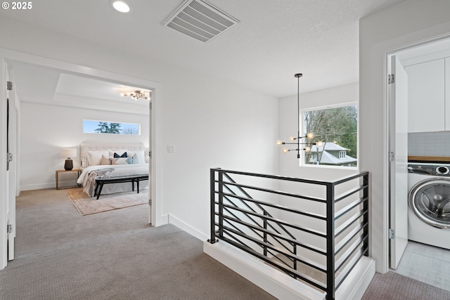 corridor featuring a notable chandelier, an upstairs landing, washer / dryer, visible vents, and carpet