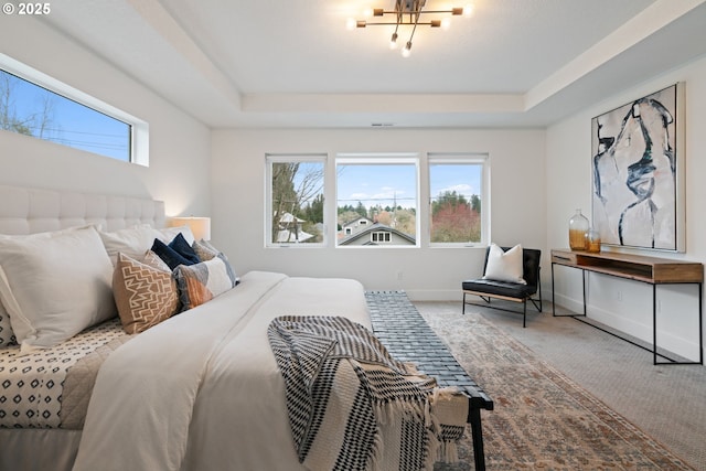 bedroom featuring a tray ceiling, a chandelier, baseboards, and carpet
