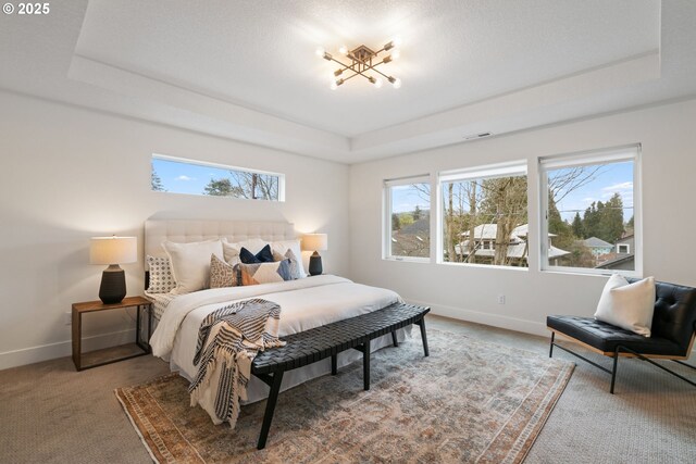 bedroom featuring baseboards, an inviting chandelier, carpet floors, visible vents, and a tray ceiling