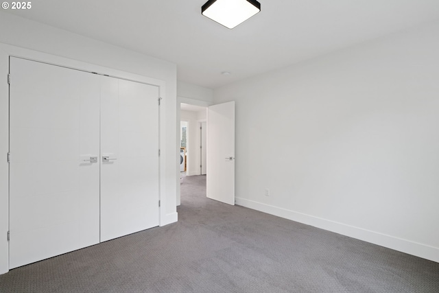 unfurnished bedroom featuring a closet, washer / clothes dryer, carpet flooring, and baseboards