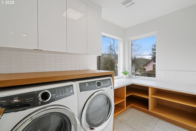 clothes washing area with cabinet space, visible vents, washer and dryer, and light tile patterned flooring