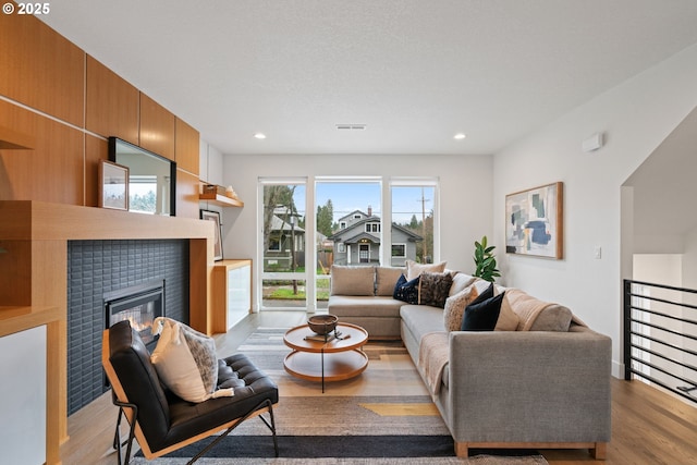 living area with visible vents, recessed lighting, a tile fireplace, and wood finished floors
