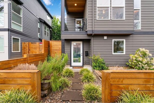 view of exterior entry featuring a balcony and fence