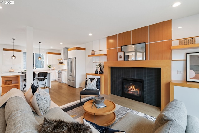 living room with light wood-type flooring, a fireplace, and recessed lighting