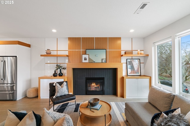 living room featuring visible vents, light wood-type flooring, recessed lighting, and a fireplace
