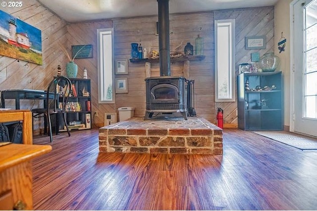 living area featuring a wood stove, wood walls, and wood finished floors
