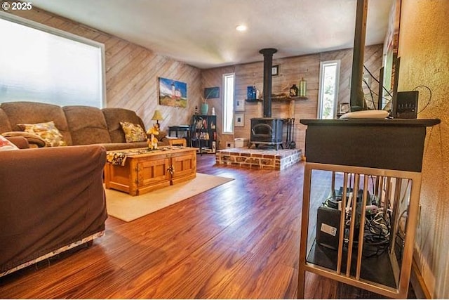 living area featuring wooden walls, a wood stove, and wood finished floors
