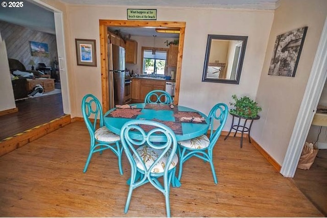 dining space featuring baseboards and light wood finished floors