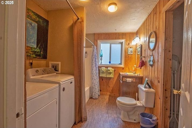 bathroom with shower / tub combo with curtain, toilet, wood walls, wood finished floors, and washer and clothes dryer