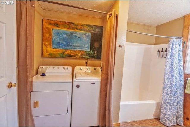 washroom with laundry area, a textured ceiling, and washing machine and dryer