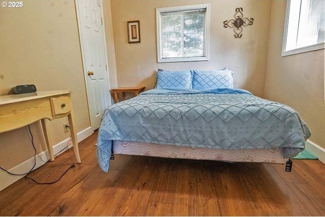 bedroom with baseboards and dark wood-type flooring