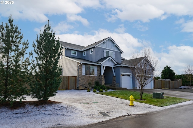 craftsman-style house featuring board and batten siding, driveway, central AC unit, fence, and an attached garage