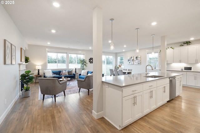 kitchen featuring stainless steel dishwasher, light wood-style floors, open floor plan, recessed lighting, and a sink