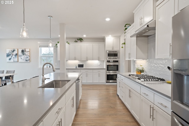 kitchen featuring appliances with stainless steel finishes, a sink, under cabinet range hood, recessed lighting, and white cabinetry