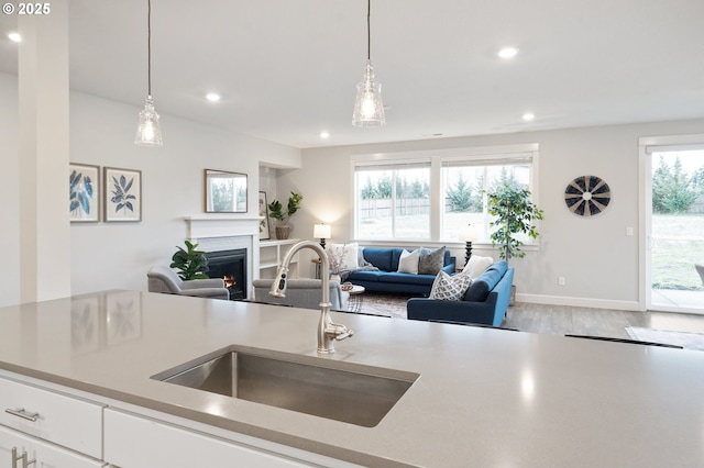 kitchen with recessed lighting, open floor plan, a lit fireplace, and a sink