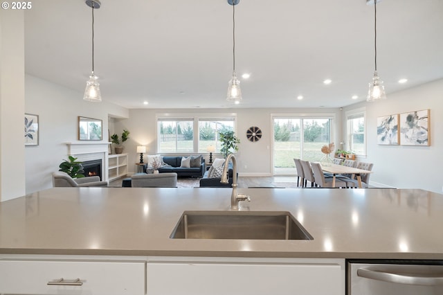 kitchen with open floor plan, a lit fireplace, recessed lighting, a sink, and dishwasher
