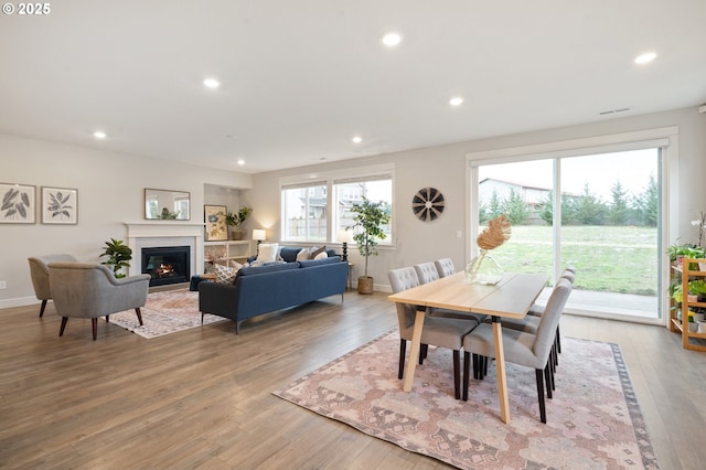 dining space with recessed lighting, light wood-style flooring, and a glass covered fireplace