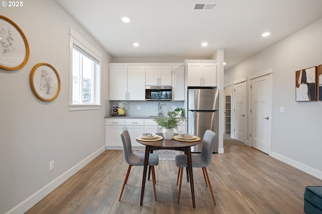 dining space featuring baseboards, recessed lighting, wood finished floors, and visible vents