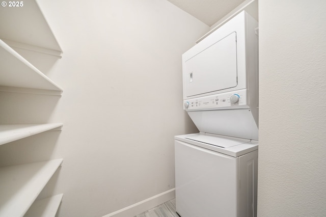 clothes washing area featuring baseboards and stacked washer and dryer