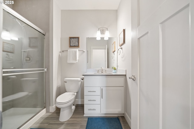 full bath featuring toilet, a shower stall, and wood finished floors
