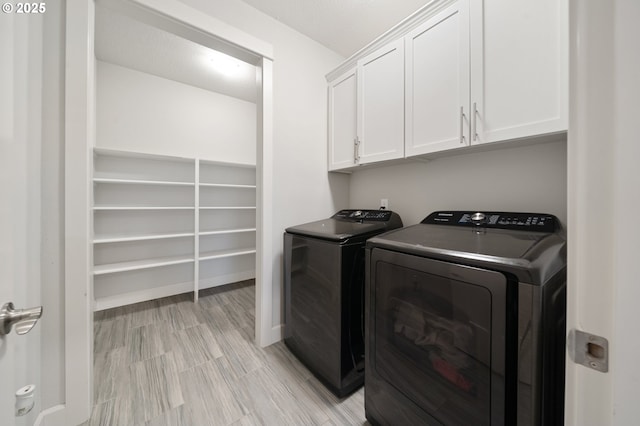 laundry area featuring cabinet space, separate washer and dryer, baseboards, and light wood finished floors