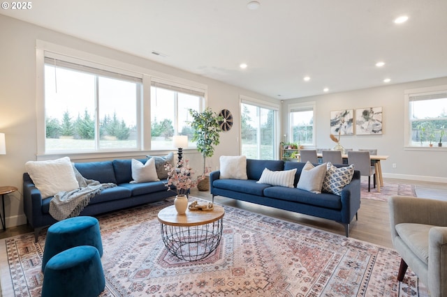 living area featuring baseboards, recessed lighting, visible vents, and light wood-type flooring
