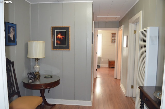 hallway featuring light wood finished floors, attic access, and a heating unit