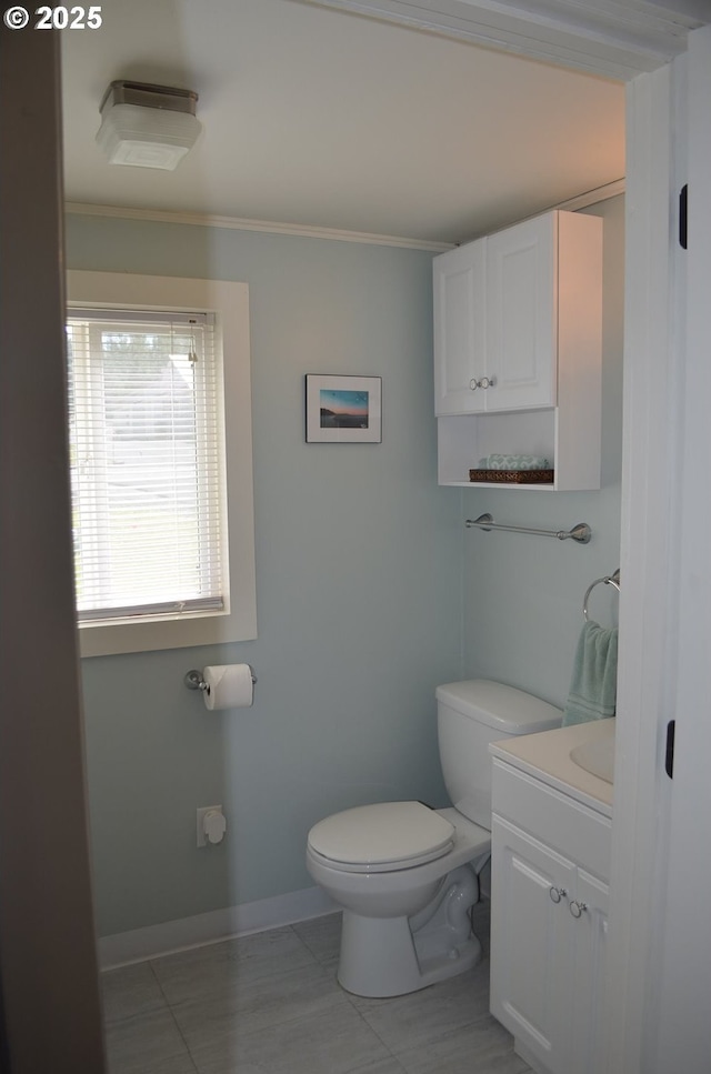 half bath featuring toilet, crown molding, tile patterned flooring, vanity, and baseboards