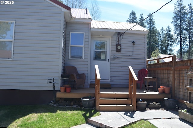 back of house with a wooden deck, metal roof, and fence