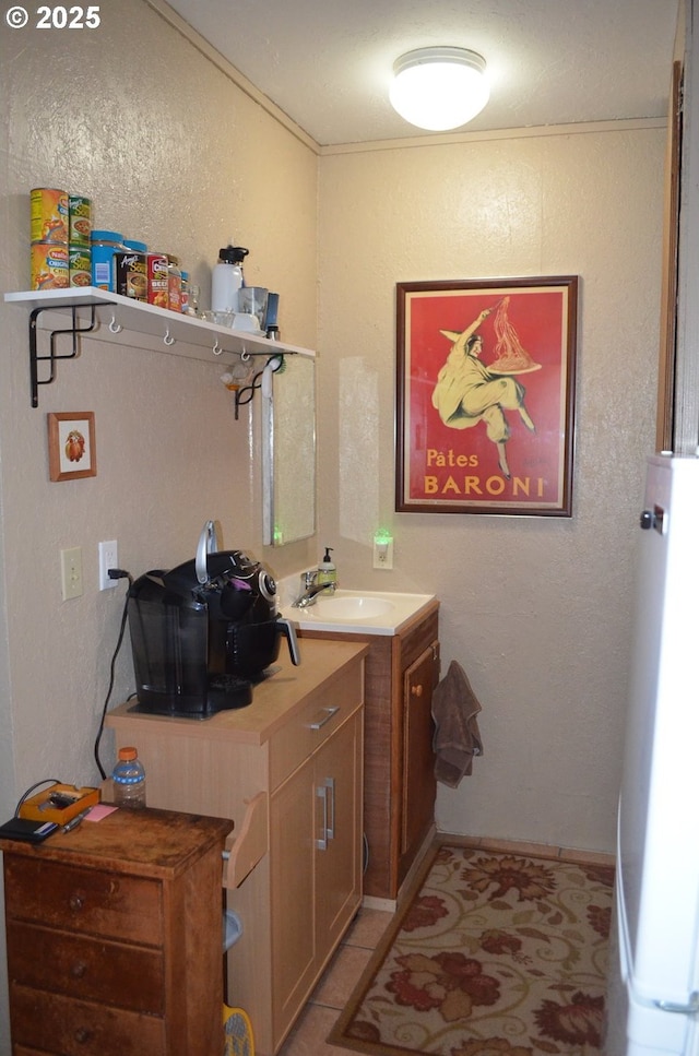 laundry area featuring a sink, a textured wall, light tile patterned floors, and water heater