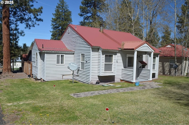 back of property featuring a lawn and metal roof