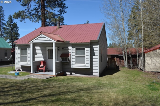 back of property featuring a yard and metal roof