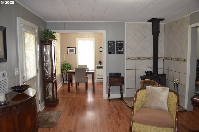 living area with ornamental molding, wood finished floors, a wood stove, and baseboards