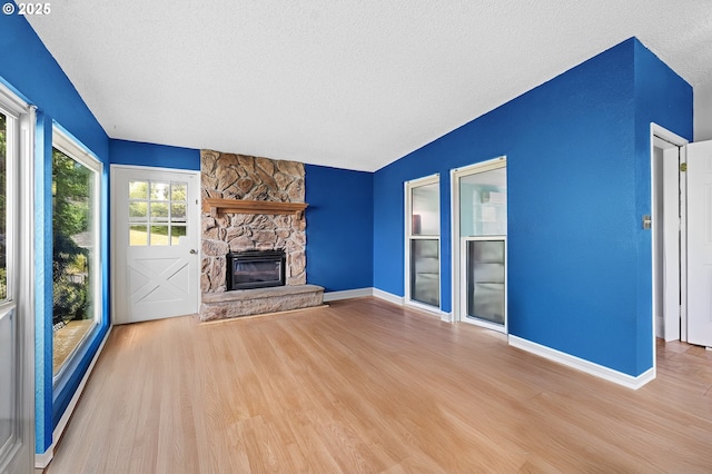 404 Chinook Ave, Astoria, OR 97103 - unfurnished living room with wood finished floors, a textured ceiling, a stone fireplace, and baseboards